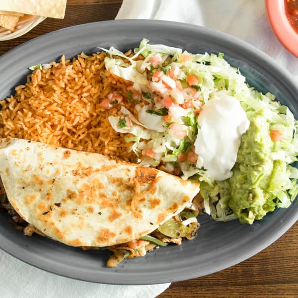 A Los Compas fajita quesadilla with rice, lettuce, pico de gallo, guacamole, and sour cream.