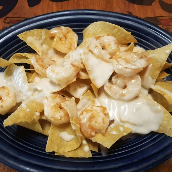 Shrimp nachos from Los Compas Raytown, with melted white cheese on a dark blue plate.