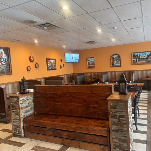 Interior of Los Compas Raytown, a Mexican restaurant, with orange walls, wooden booths, and framed art.