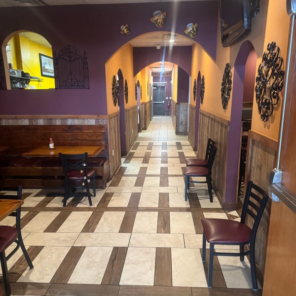 A long, colorful hallway with purple and orange walls, leading to restrooms in Los Compas Raytown.