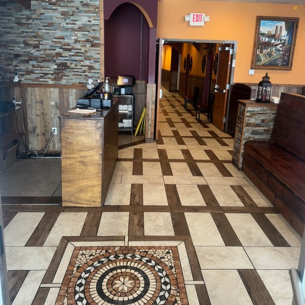 The interior of Los Compas Raytown features a tiled floor, wooden benches, and a stone-accented wall.